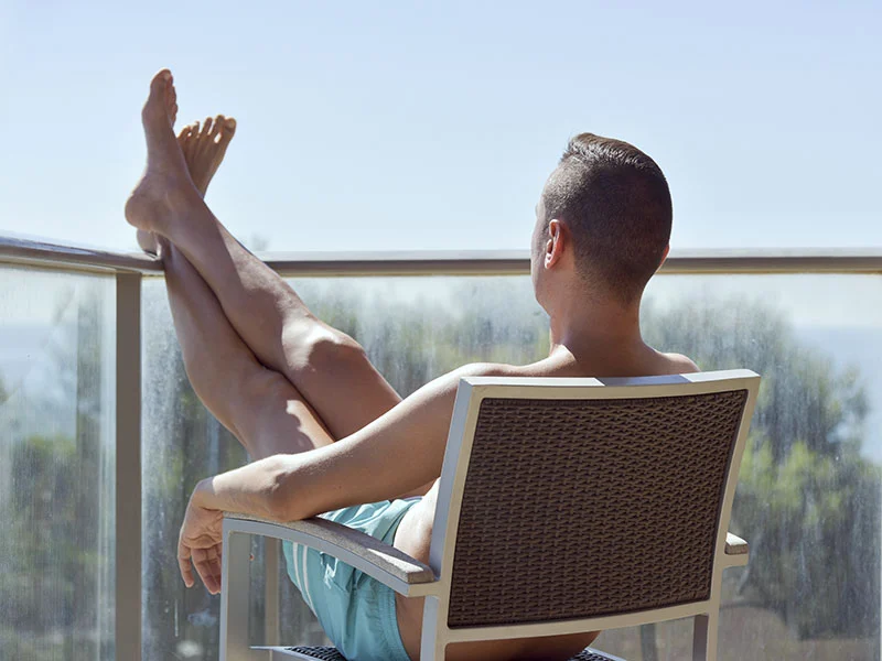 A person relaxes on a sunny balcony, reflecting the importance of self-care in caregiving. The Christopher Smith Foundation emphasizes caregiver support and recognition within the…| A Non Profit For Caregivers | Christopher Smith Foundation