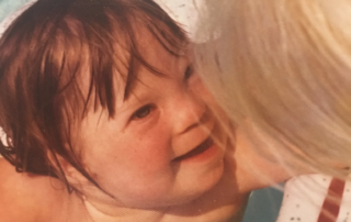 A child with brown hair smiles while in a pool, hugged by a caregiver. This image embodies the Christopher Smith Foundation's mission of caregiver support and recognition within the disability community.| A Non Profit For Caregivers | Christopher Smith Foundation