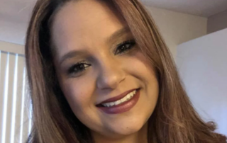 A smiling woman with long hair stands indoors, embodying the spirit of caregiver support promoted by the Christopher Smith Foundation, which honors caregivers of people with disabilities.| A Non Profit For Caregivers | Christopher Smith Foundation