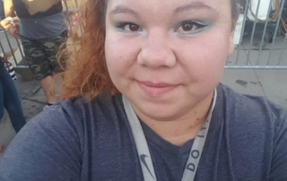 A smiling woman with blue eye makeup and a blue hair bow takes a selfie outdoors, highlighting the Christopher Smith Foundation's mission of caregiver support and disability advocacy.| A Non Profit For Caregivers | Christopher Smith Foundation