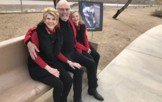 A family sits on a park bench smiling, with a photo of a person in a wheelchair beside them, symbolizing caregiver support by the Christopher Smith Foundation.| A Non Profit For Caregivers | Christopher Smith Foundation