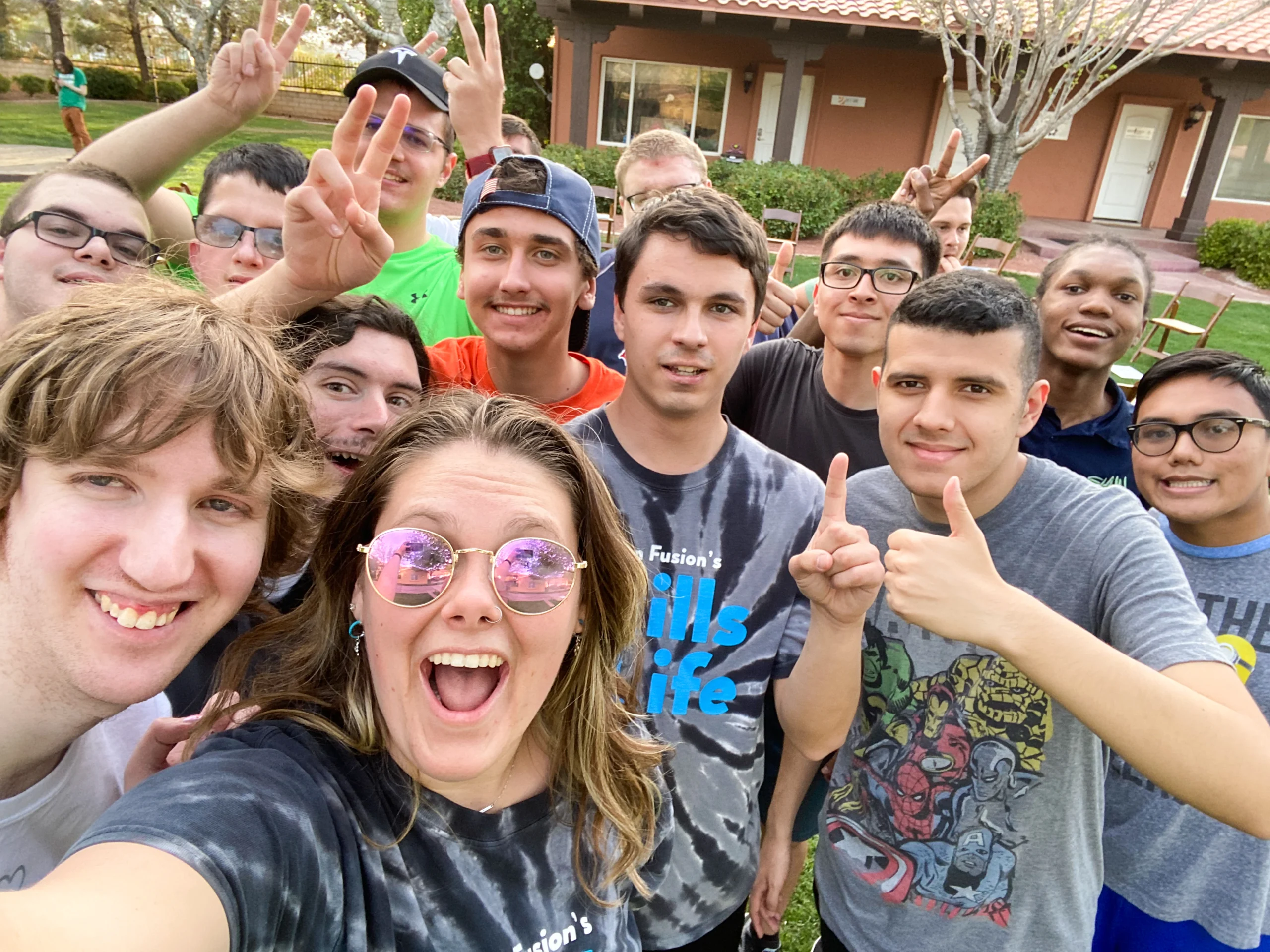 A group of young people, some wearing glasses and colorful t-shirts, smile and make peace signs outdoors, embodying joy and community. This image highlights the essence of caregiver support and disability advocacy by the Christopher Smith Foundation.| A Non Profit For Caregivers | Christopher Smith Foundation