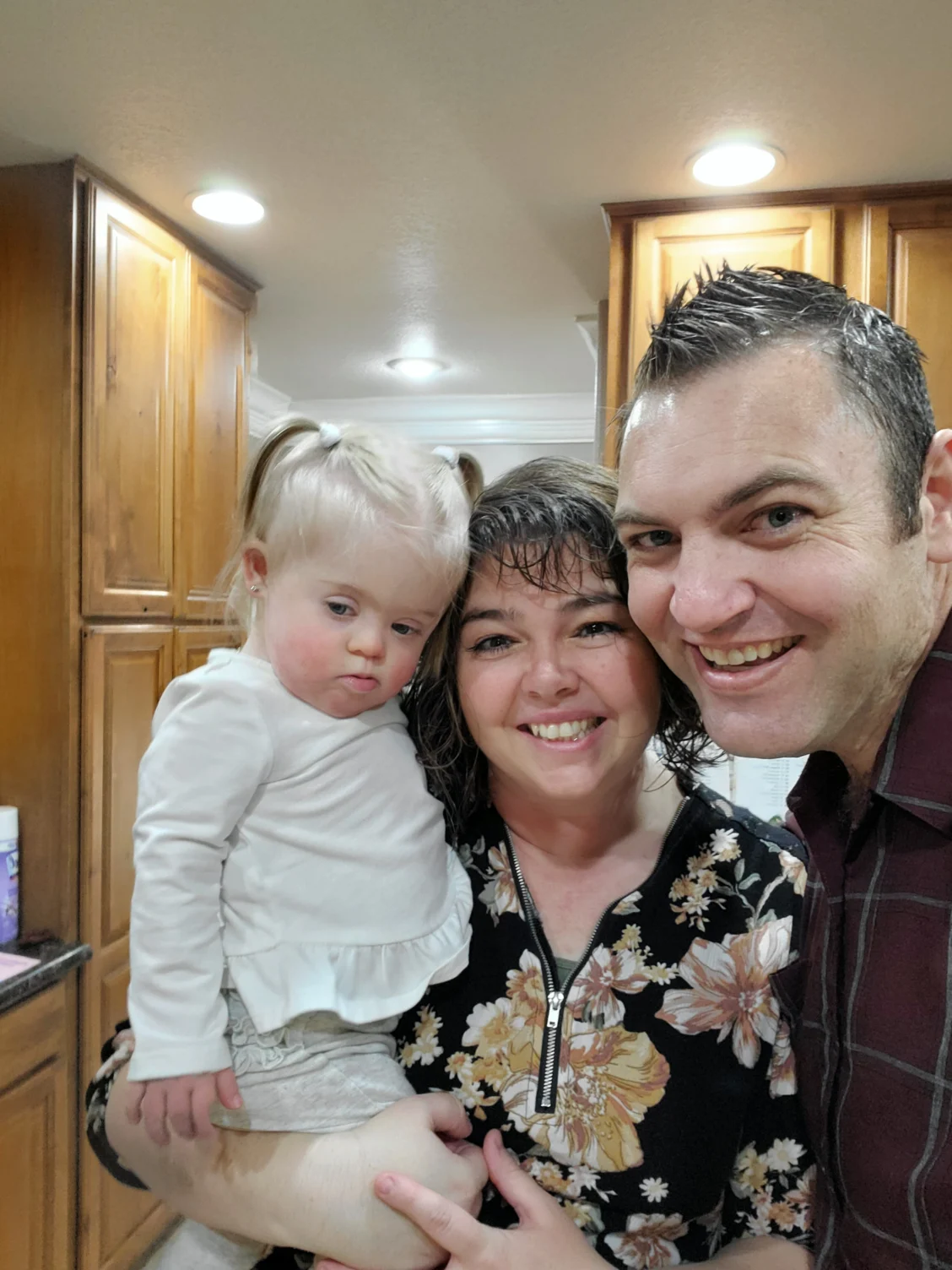 A smiling family with a young child with Down syndrome is embraced by two adults, highlighting family caregivers. The Christopher Smith Foundation supports caregivers of people with disabilities through recognition and advocacy.| A Non Profit For Caregivers | Christopher Smith Foundation