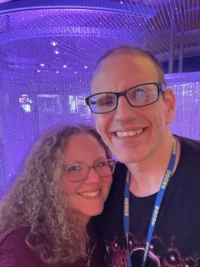 A smiling man and woman pose together under purple lights, celebrating caregiver support at a Christopher Smith Foundation event, highlighting the importance of caregivers in the disability community.| A Non Profit For Caregivers | Christopher Smith Foundation