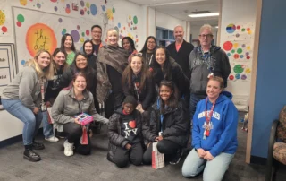 A diverse group of smiling people, including family caregivers and children, gather in a colorful room for a Christopher Smith Foundation event, highlighting caregiver support and community engagement.| A Non Profit For Caregivers | Christopher Smith Foundation