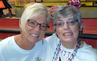 Two women smiling together at a colorful indoor venue, showcasing caregiver support and friendship within the disability community, reflecting the Christopher Smith Foundation's mission of recognizing caregivers of people with disabilities.| A Non Profit For Caregivers | Christopher Smith Foundation
