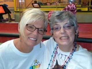 Two women smiling together at a colorful indoor venue, showcasing caregiver support and friendship within the disability community, reflecting the Christopher Smith Foundation's mission of recognizing caregivers of people with disabilities.| A Non Profit For Caregivers | Christopher Smith Foundation