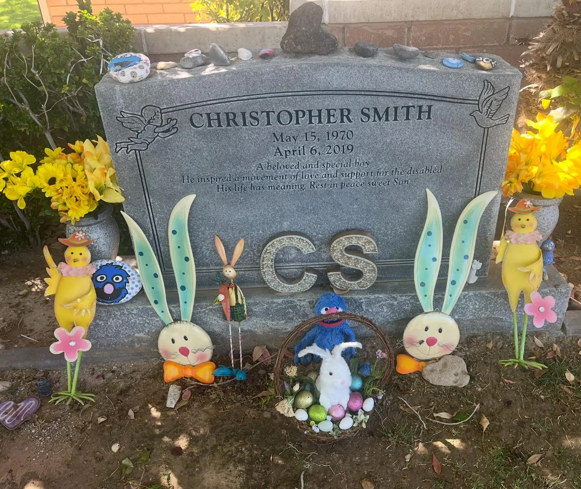 A gravestone for Christopher Smith with decorative bunnies and flowers, representing the Christopher Smith Foundation's mission of disability advocacy and caregiver support.| A Non Profit For Caregivers | Christopher Smith Foundation