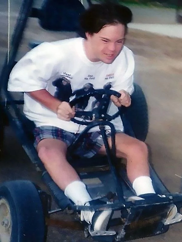 A young person joyfully drives a go-kart on a dirt path, showcasing a moment of freedom and excitement. This image highlights the Christopher Smith Foundation's commitment to disability advocacy and supporting caregivers of people with disabilities.| A Non Profit For Caregivers | Christopher Smith Foundation